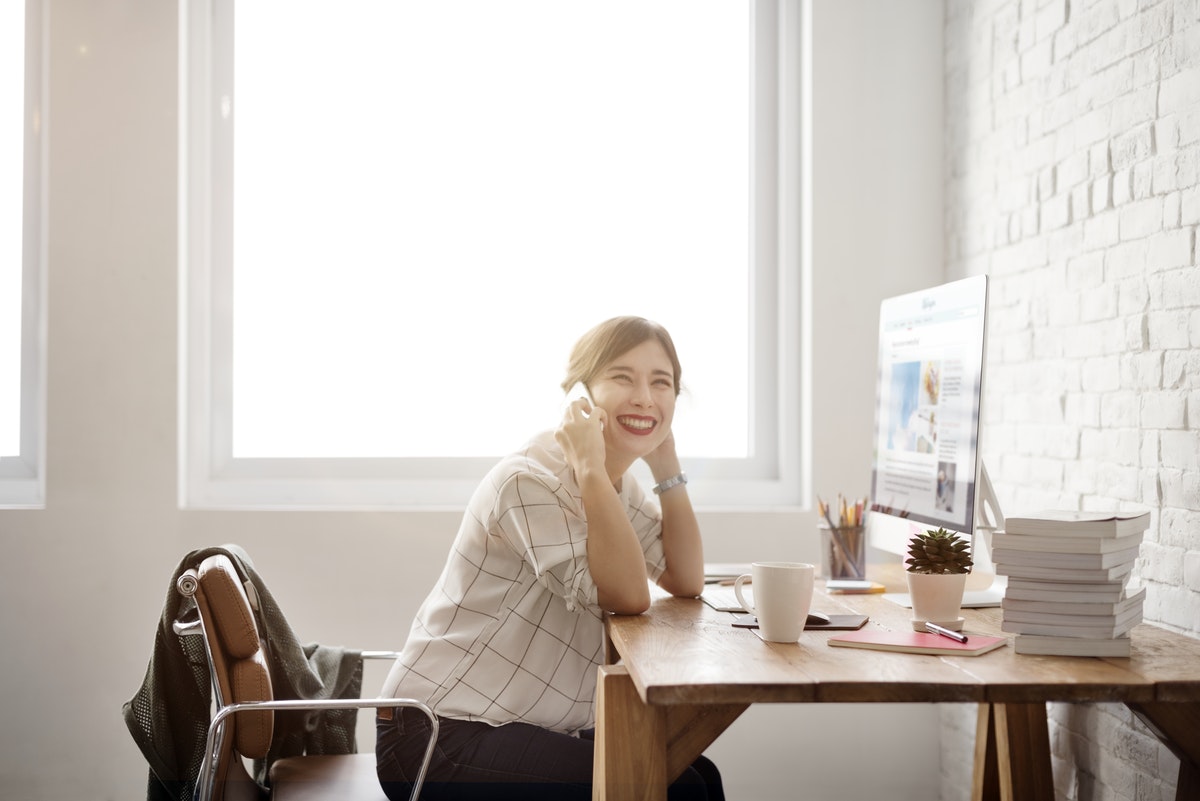 Woman sitting at her desk talking on the phone and smiling