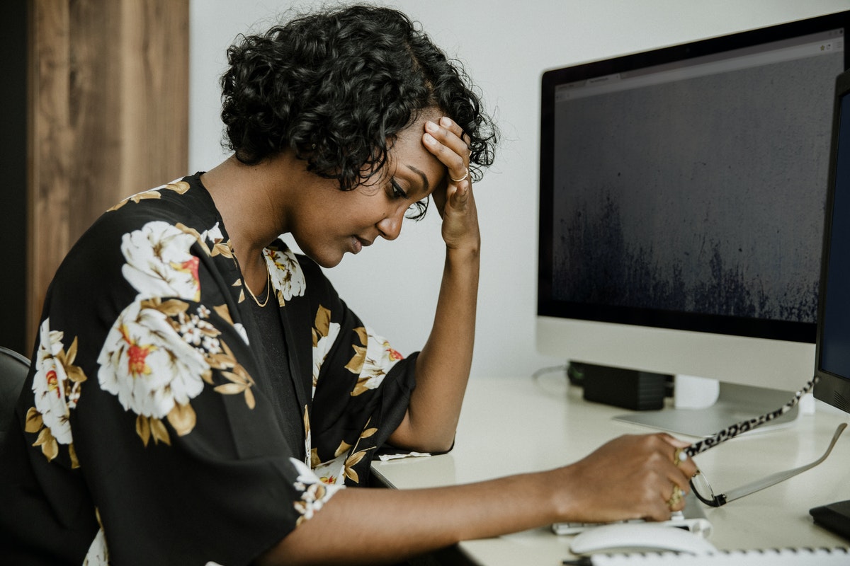 Woman sitting in front of computer, looking stressed.