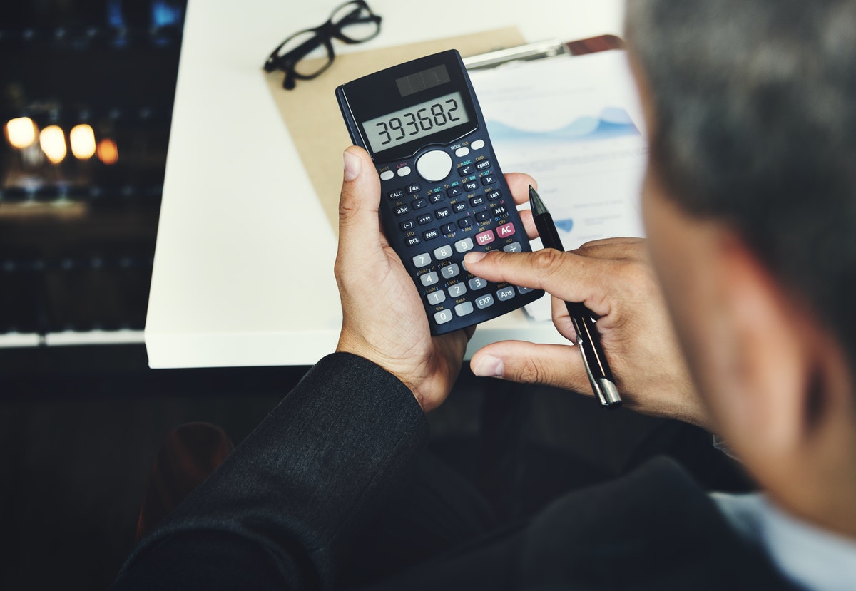 Person using calculator with financial statements in background